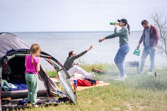 A family making food in front of their tent