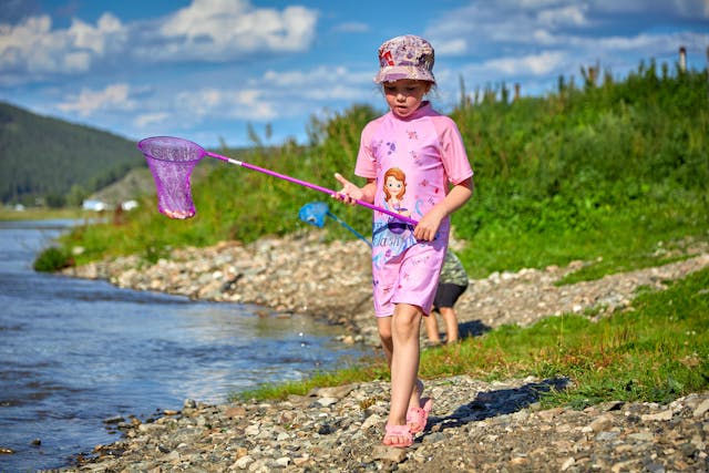 A girl holding a net on a stick while standing near water