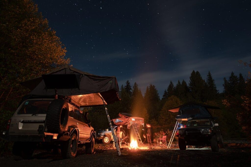 People with camping gear, camper cars, tents, fire, outdoor, night camping