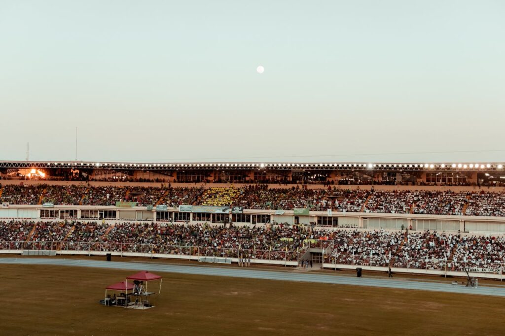 a bustling crowd fills the stadium under a clear evening sky, creating a vibrant atmosphere