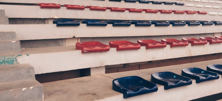 rows of red, blue, and white stadium seats in an empty arena