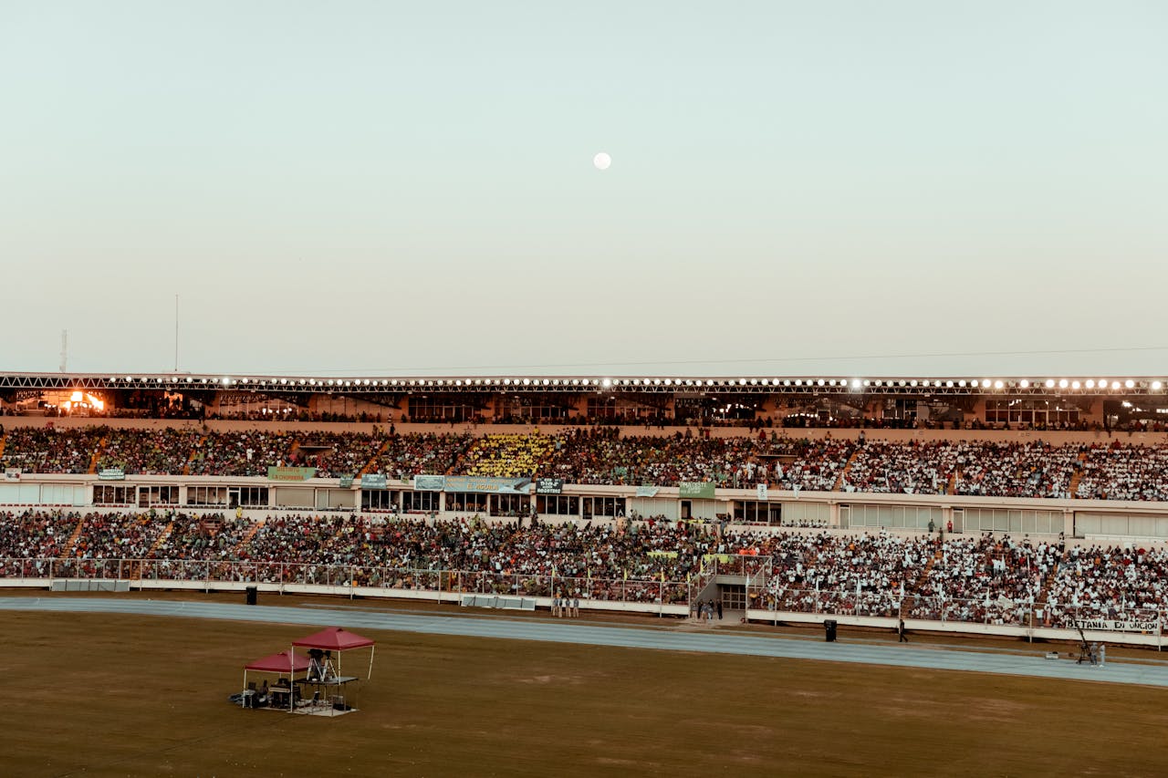 a bustling crowd fills the stadium under a clear evening sky, creating a vibrant atmosphere
